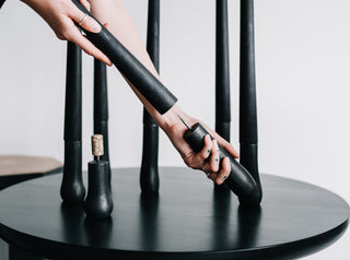 Woman placing a black 100% beeswax grove candle stick onto the holder's spike