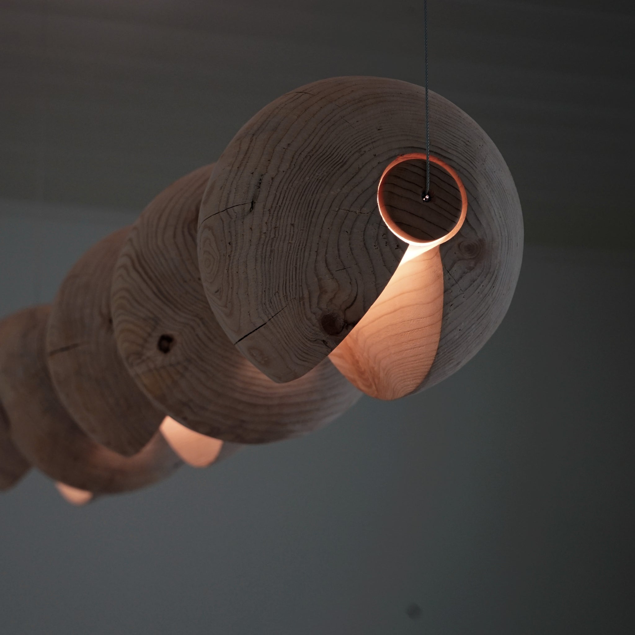 Statement light made from 5 cedar spheres wrapped around a light rod suspended by thin cables.