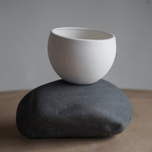 white ceramic pot sitting on a stone
