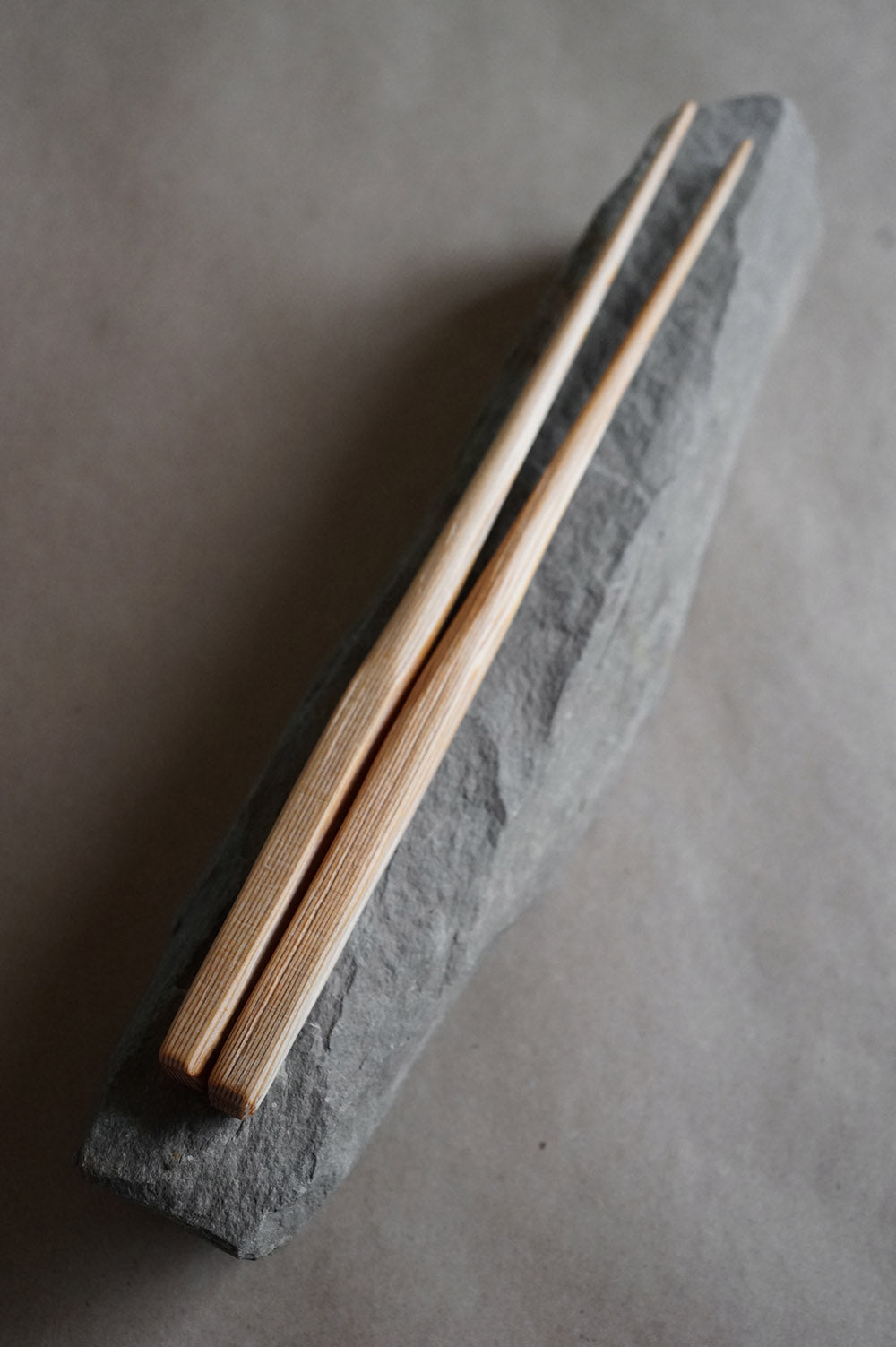 hand whittled douglas fir chopsticks laying on a rock