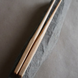 hand whittled douglas fir chopsticks laying on a rock