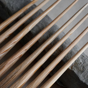 8 hand whittled douglas fir chopsticks laying on a rock