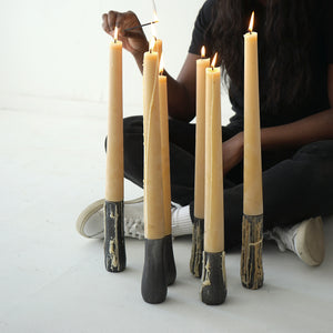 woman lighting 100% beeswax Grove candles sitting on iron Grove candle holders of various sizes