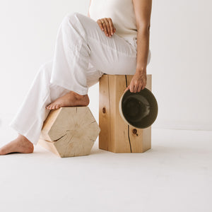 Woman sitting on Hexagonal shaped solid hemlock stool with an oiled finish.