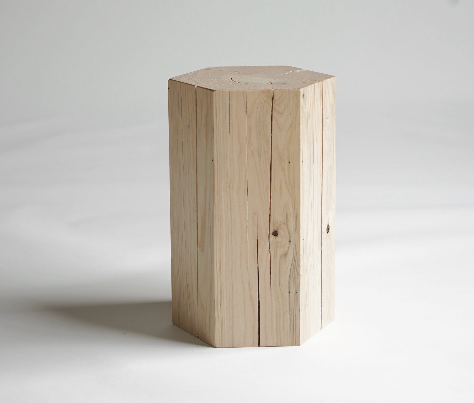 Hexagonal shaped solid hemlock stool with an oiled finish.