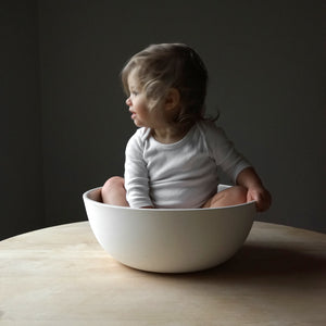 Baby girl sitting in jumbo white porcelain serving bowl