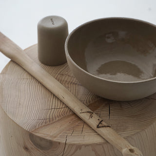 9" oatmeal stone serving bowl sitting on a wood stool 